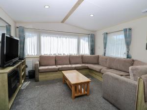 a living room with a couch and a tv at Caravan 325 in Lowestoft