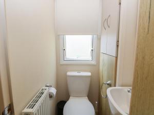 a bathroom with a toilet and a sink and a window at Caravan 325 in Lowestoft +11 photos