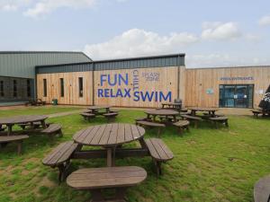 a group of picnic tables in front of a building at Caravan 325 in Lowestoft