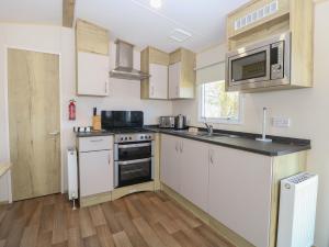 a kitchen with white cabinets and a microwave at Caravan 325 in Lowestoft