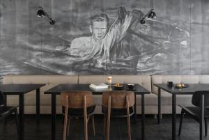 ein Esszimmer mit zwei Tischen und einem Wandgemälde in der Unterkunft Skuggi Hotel by Keahotels in Reykjavík