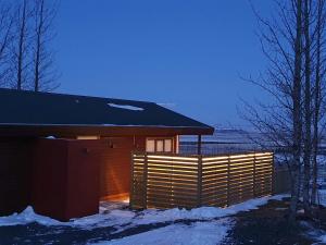 a wooden cabin with a fence in the snow at Úthlíd Cottages in Úthlid