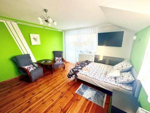 a bedroom with green walls and a bed and chairs at Zaciszny domek in Słupsk