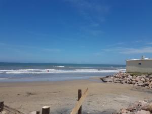 a beach with a building and the ocean at Los Lachos in Aguas Dulces