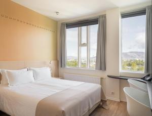 a hotel room with a bed and two windows at Reykjavik Lights Hotel by Keahotels in Reykjavík