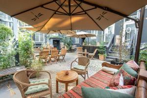 a patio with chairs and tables and an umbrella at Lulu Guldsmeden in Berlin