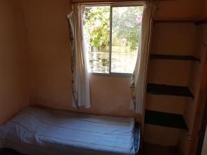 a small bedroom with a bed and a window at Los Lachos in Aguas Dulces