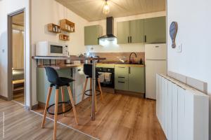 a kitchen with green cabinets and bar stools at L'Escapade Pannessac troisième étage in Le Puy-en-Velay
