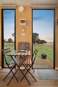 a table and two chairs in front of a door at Lara Grove Cottage 2 by Tiny Away in Purdeet +13 photos