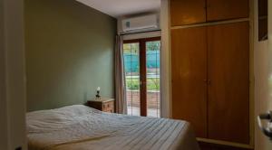 a bedroom with a bed and a sliding glass door at El descanso - Costa Azul in Villa Carlos Paz