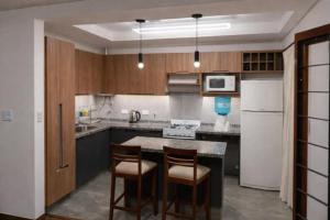 a kitchen with two chairs and a kitchen island with a refrigerator at El descanso - Costa Azul in Villa Carlos Paz
