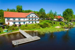 a large house with a dock in the middle of a lake at Sielanka nad Junem in Mrągowo