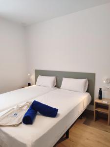 a large white bed with a blue pillow on it at Hotel Calella by Beatriz Hoteles in Calella