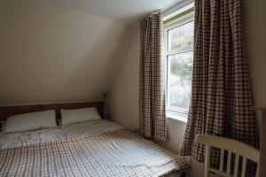 a small bedroom with a bed and a window at Kathleen's Croft, charming detached croft house in Torridon