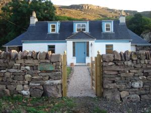 a white house with a stone fence in front of it at Kathleen's Croft, charming detached croft house in Torridon