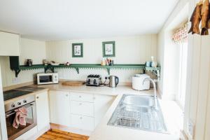 a kitchen with a sink and a microwave at Kathleen's Croft, charming detached croft house in Torridon
