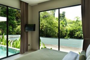 a bedroom with a bed and a large glass window at 3BR Nava villa Ubud in Ubud