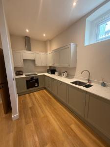 a kitchen with white cabinets and a wooden floor at Windsor Flat 90A in Windsor