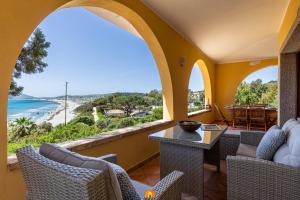 an arched porch with chairs and tables and a view of the beach at Villa Teresa Simius Beach Front in Simius