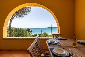a table with a view of the ocean from a window at Villa Teresa Simius Beach Front in Simius