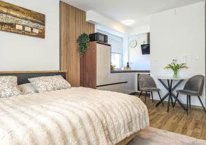 a bedroom with a bed and a table and a kitchen at Trend Apartman in Bük