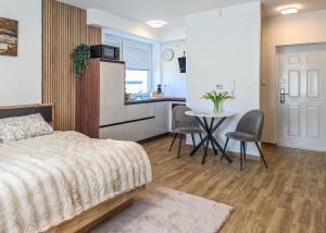 a bedroom with a bed and a table and a kitchen at Trend Apartman in Bük