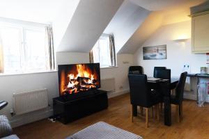 a living room with a fireplace and a dining table at Harbour Penthouse Whitby in Whitby