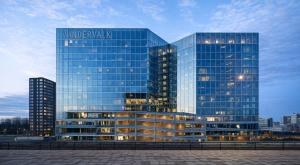 a large glass building with a sign on it at Van der Valk Hotel Amsterdam Zuidas-Rai in Amsterdam