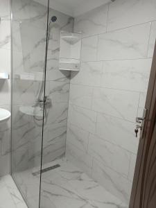 a bathroom with a shower with white marble tiles at Casa Crina in Băile Herculane +39 photos