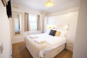 a bedroom with a bed with white sheets and a window at Harbour Penthouse Whitby in Whitby