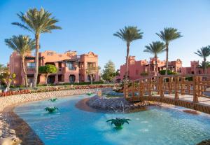 a pool at a resort with palm trees and houses at Charmillion Sea Life Resort in Sharm El Sheikh