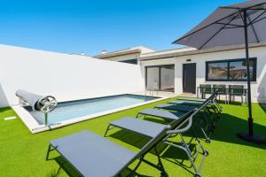 a patio with chairs and an umbrella and a pool at Villa Emilio with private pool in Mariquiteira