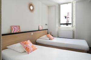 a room with two beds and a window at Hôtel Restaurant Le Commerce in Navarrenx