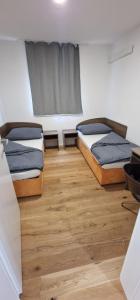 two beds in a room with wooden floors and a window at S3 Stadl Paura in Stadl-Paura