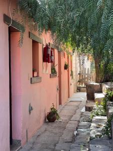 an alley with a pink building with potted plants at Kantuta Hospedaje in Tilcara