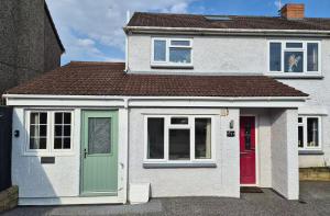a white house with a red door and windows at The Apartment at Charles Road in Frome