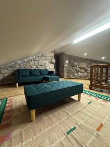 a living room with blue couches and a stone wall at Casa D'Avó Carmen in Ventosa