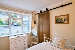 a bedroom with a bed with a dresser and a window at The Apartment at Charles Road in Frome