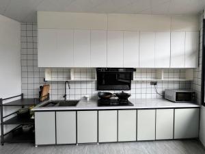 a kitchen with white cabinets and a stove at 枫江月 in Fenghuang County +17 photos