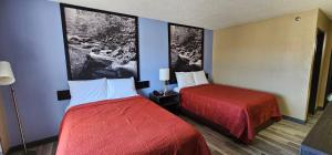 a hotel room with two beds and two pictures on the wall at Gardner Inn in Gardner