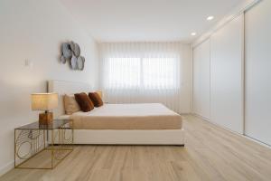 a white bedroom with a bed and a table at Villa Emilio with private pool in Mariquiteira