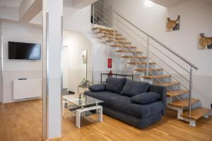 a living room with a blue couch and stairs at Paky Appartements 00317 in Bruck an der Leitha