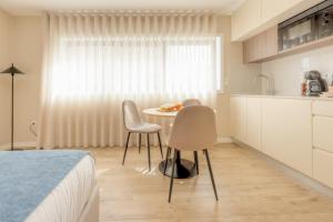 a bedroom with a table and two chairs in front of a window at Calvário Suites II in Chaves