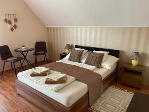 a bedroom with a large bed with two chairs and a table at Alfa Apartman in Harkány +37 photos