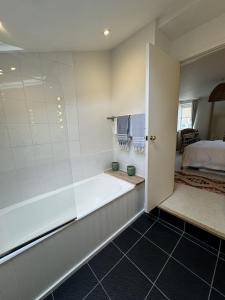 a bathroom with a bath tub and a bed at The Old Barn in Farthinghoe +15 photos