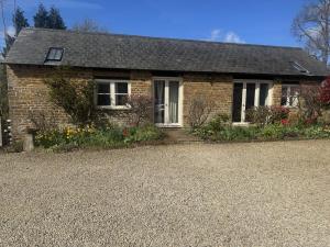 a brick house with a gravel driveway at The Old Barn in Farthinghoe