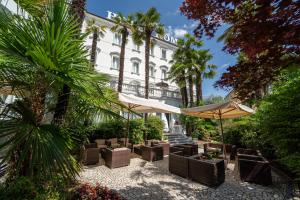 a patio with chairs and umbrellas in front of a building at Hotel Terme Roma in Abano Terme