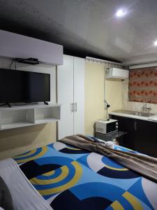 a room with a bed with a tv and a kitchen at The wood Guest house in Pretoria