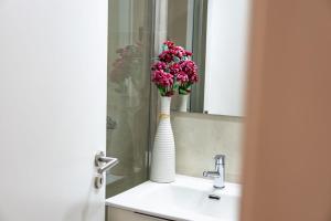 a bathroom sink with a white vase with pink flowers in it at Viosinho guest house in Alijó