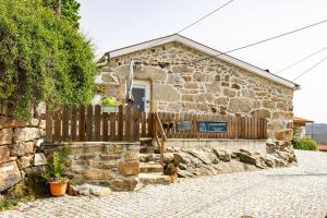 a stone house with a wooden fence and a gate at Viosinho guest house in Alijó